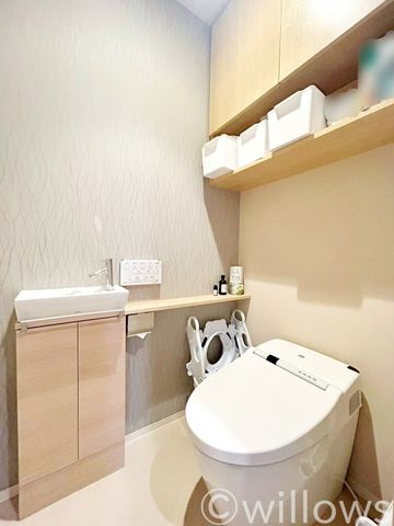 タンクレス型のトイレはお掃除も簡単。空間を広く使う工夫が随所に見受けられます。 より快適にご利用いただくために、人気のウォシュレットタイプを採用。上部の吊戸棚はトイレ用品の収納が可能です。